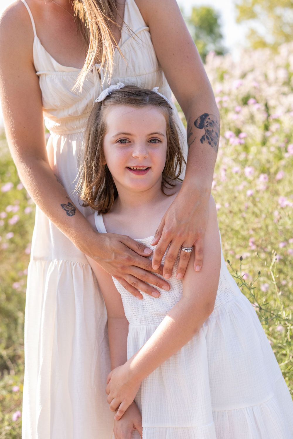 A series of soft, ethereal photos in a wildflower field showing tender moments between parent and child in white dresses.
