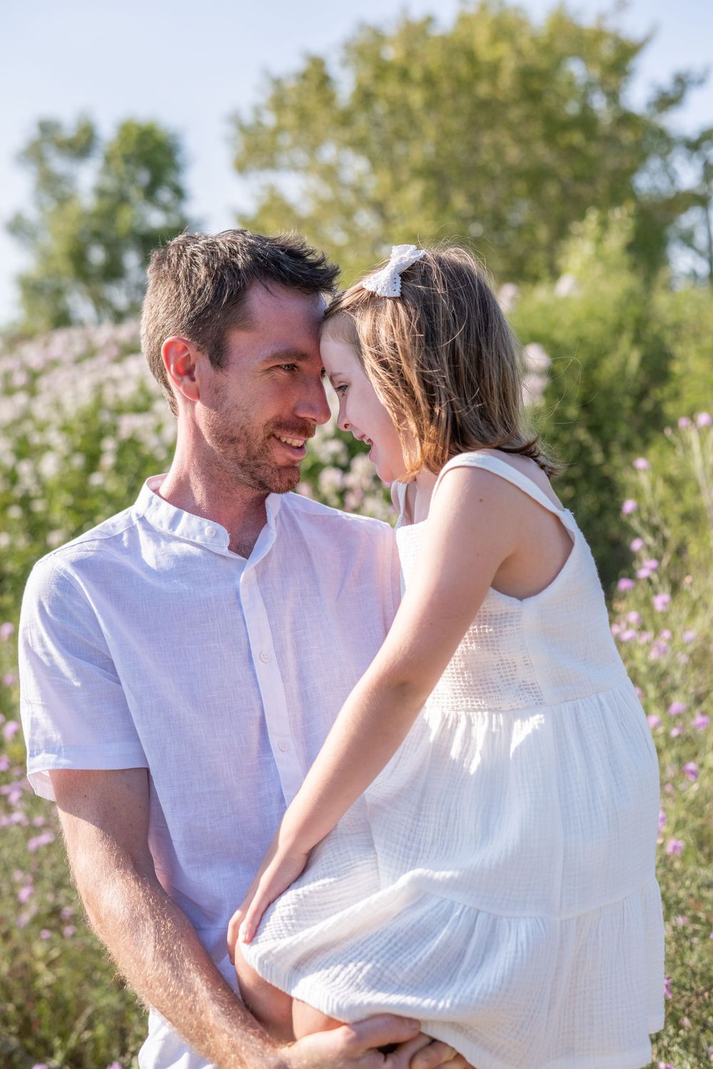 A couple shares intimate moments together in a sunny outdoor setting with trees in the background. Quinte West