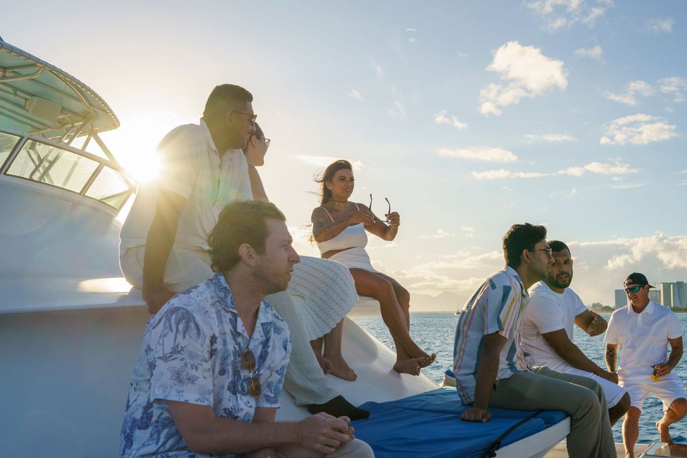 Sunset yacht party with guests relaxing on deck against beautiful ocean backdrop.
