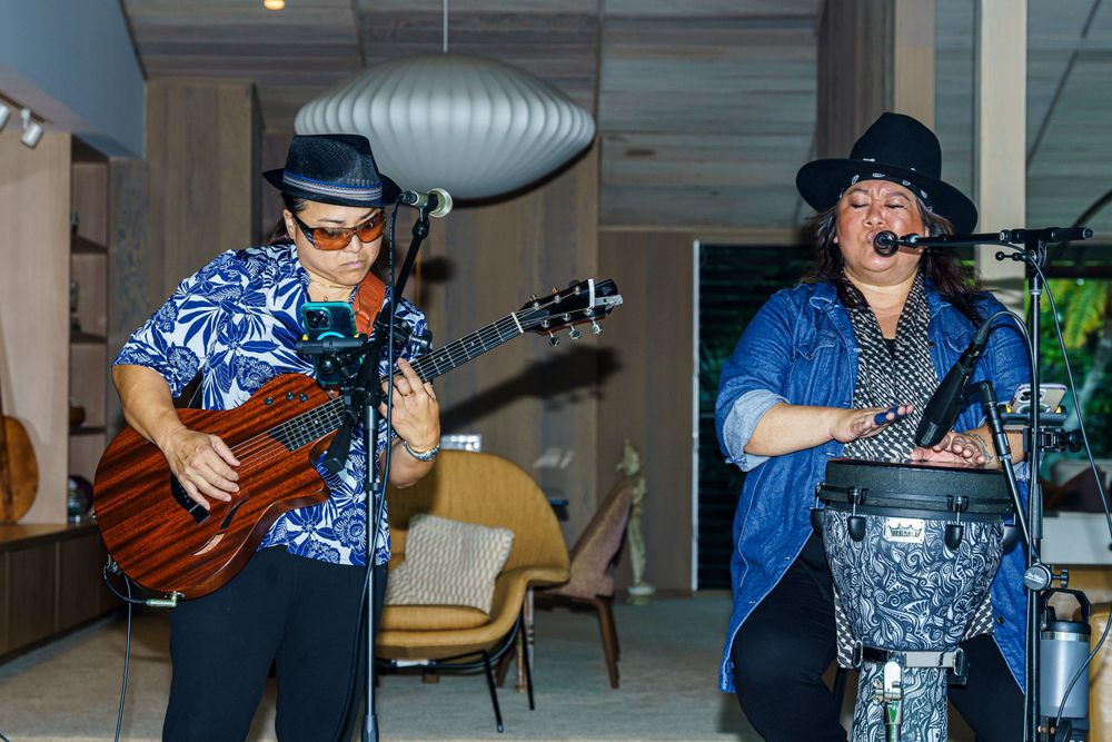 Musicians performing with instruments at an outdoor tropical venue.
