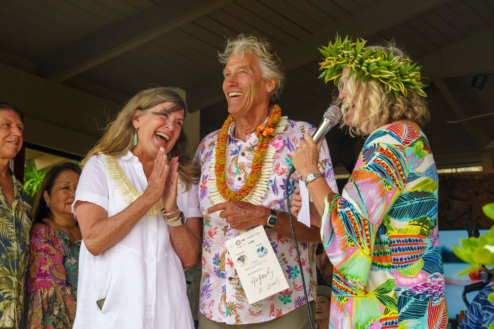 Party guests in tropical attire laughing and celebrating at an outdoor event.
