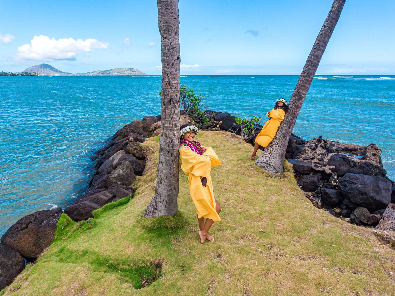 Group posed together on sandy beach with majestic mountain backdrop on Hawaiian shore.