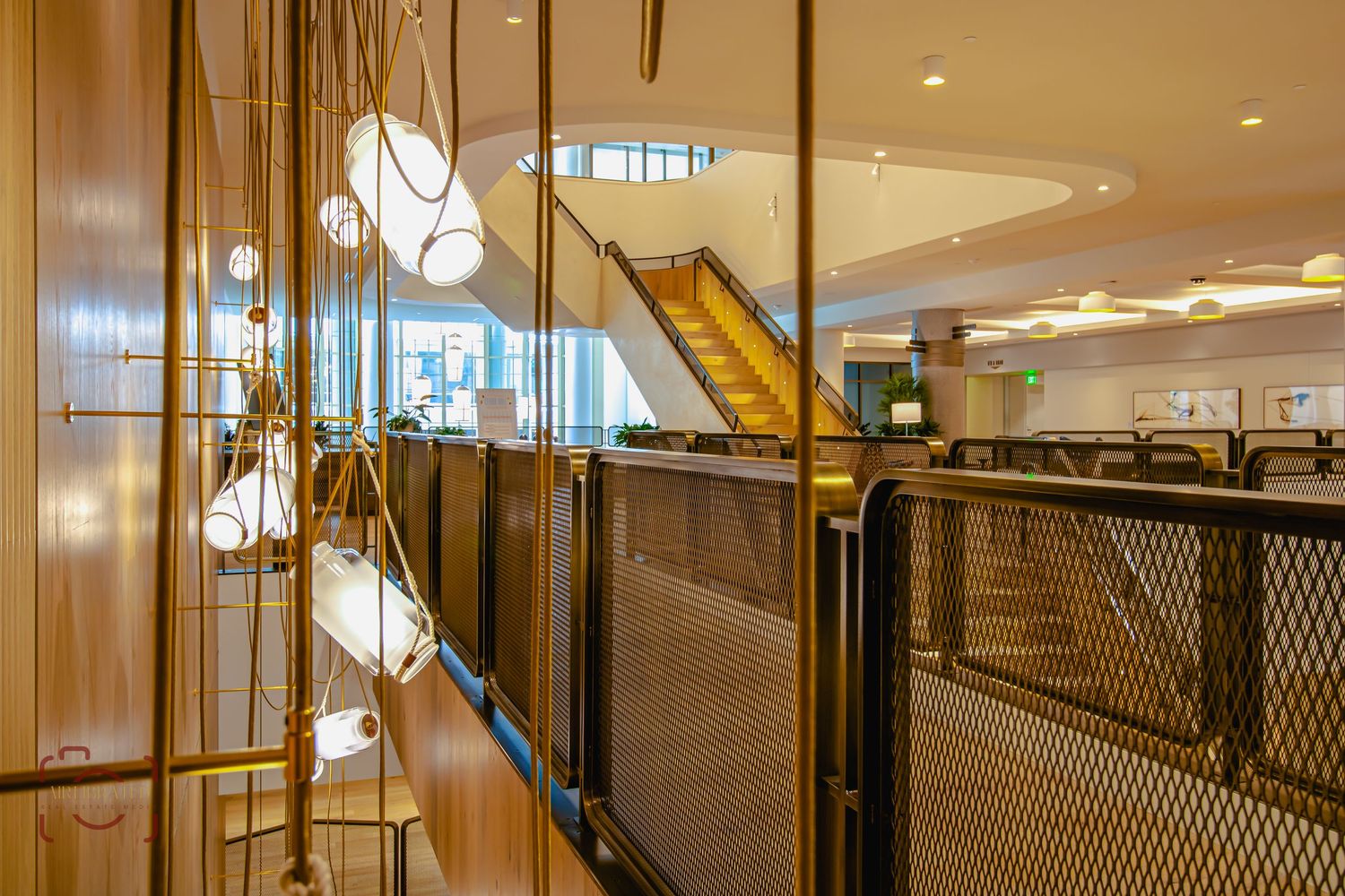 Modern interior hallway with pendant lights and metal railings featuring a wooden staircase.