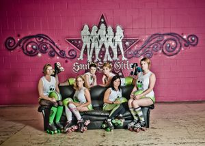 6 women in roller derby clothing sitting on couch in various posing for team photograph