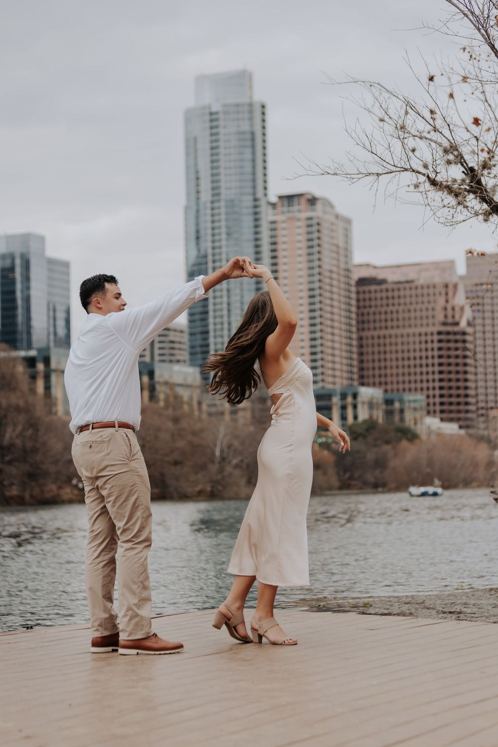 Couple dancing on a waterfront dock with Austin Texas city skyline in the background.