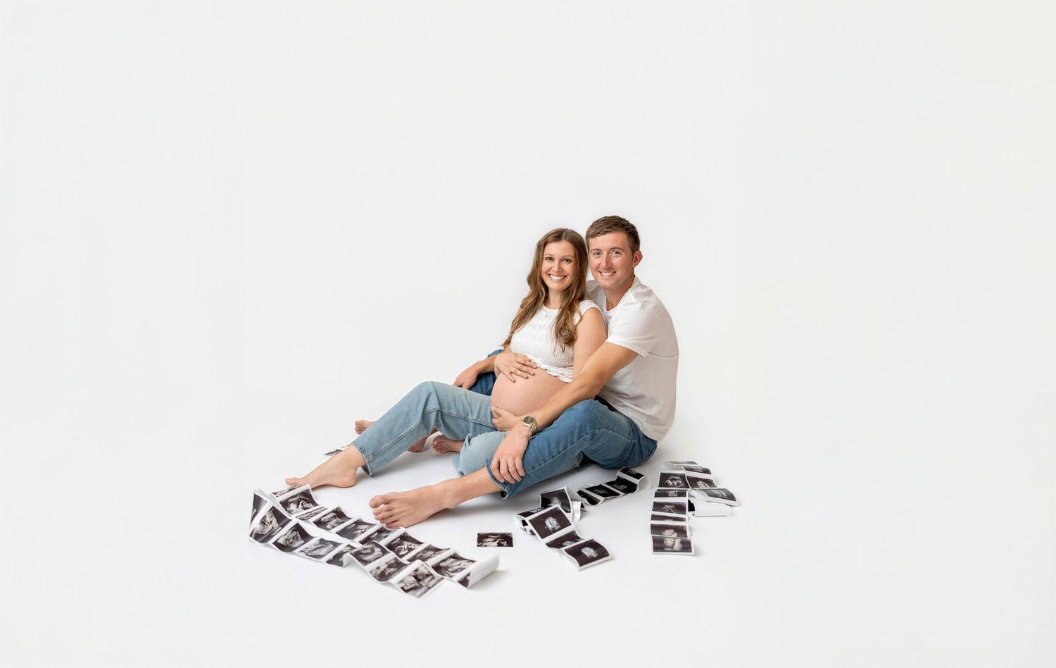 Pregnant couple with ultrasound photos during a studio maternity session in Clear Lake, Iowa