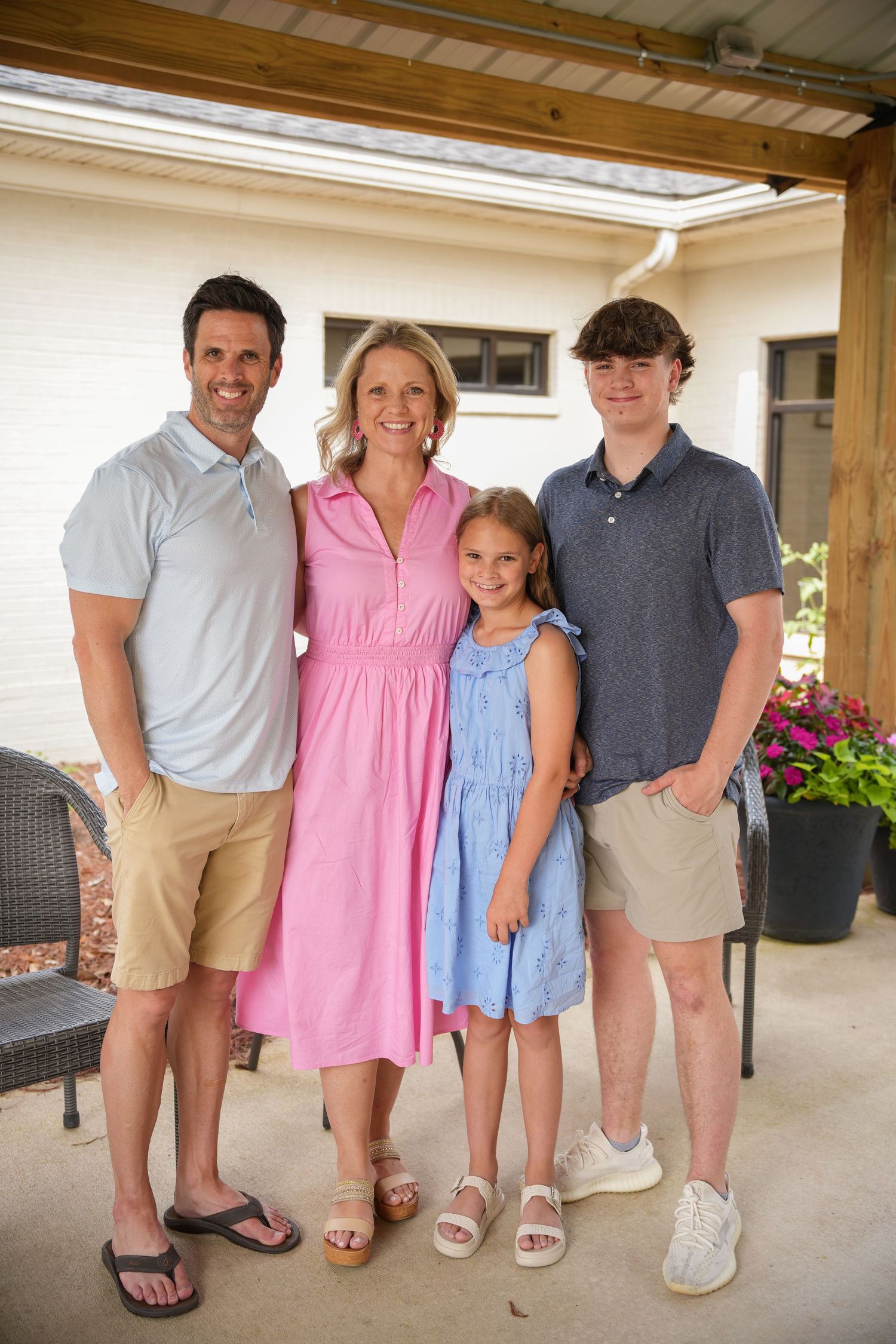 A family group poses together wearing coordinated summer outfits on a patio.