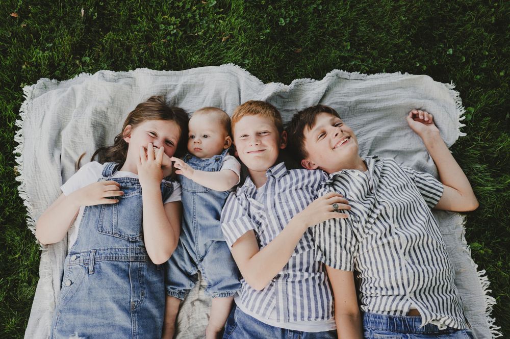 Group lying on white blanket against grass wearing coordinating denim and stripes.