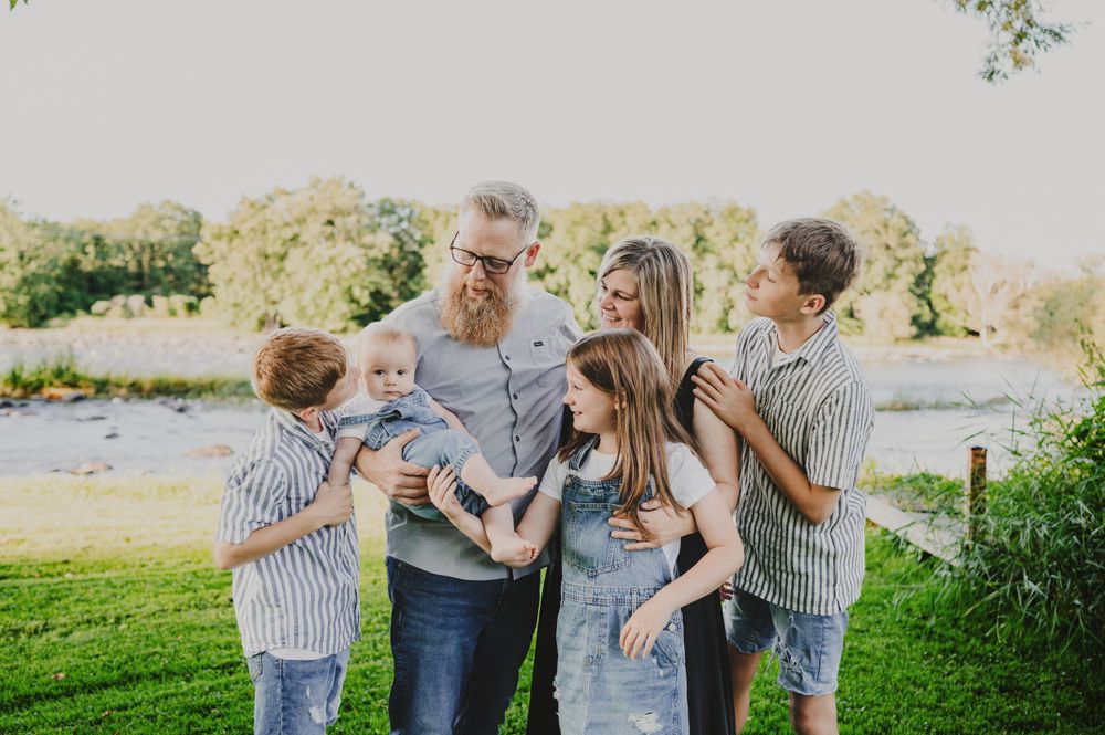 A family group shares a close moment together on a sunny day by the water.