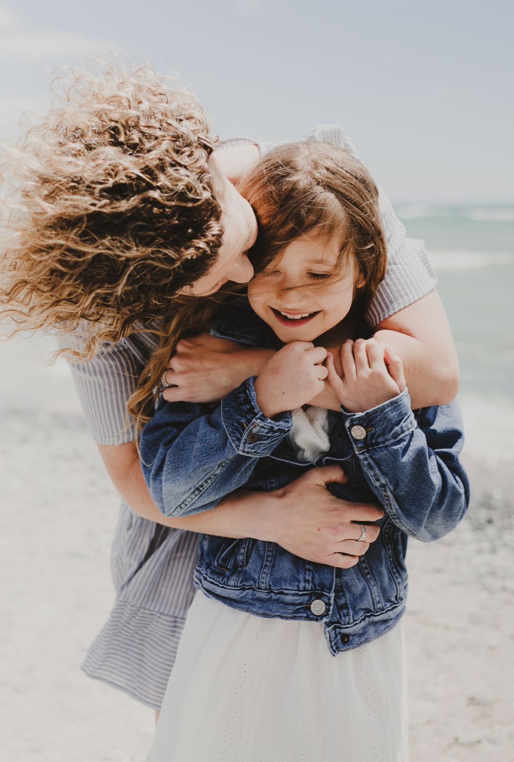 Joyful embrace captured between two people on a breezy beach.