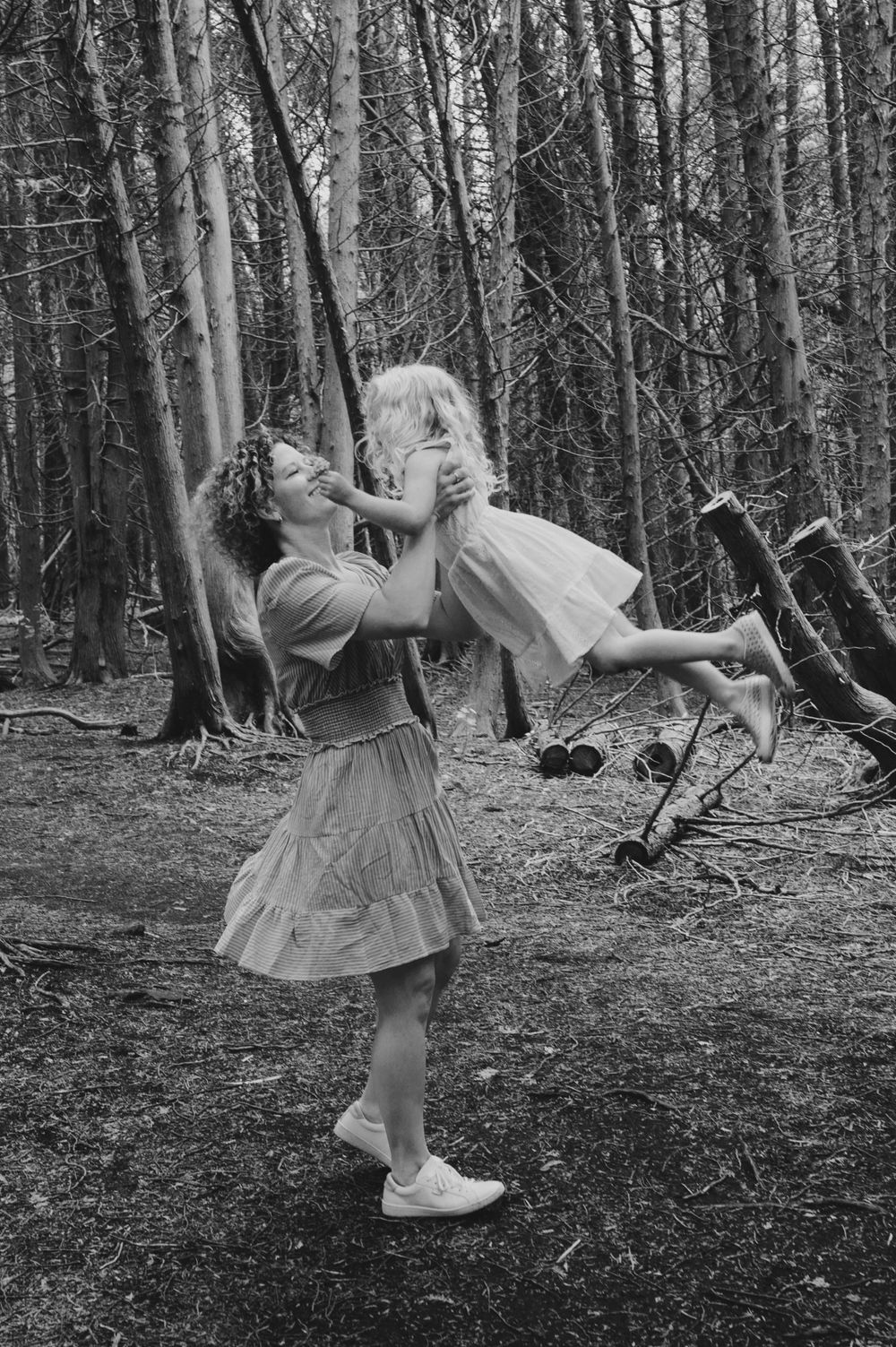 A joyful moment of play captured in black and white among forest trees.