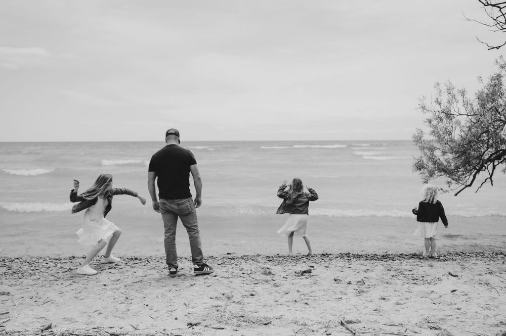 Silhouette of a family enjoying playtime together on a beach at sunset.