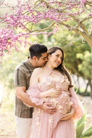 A romantic photoshoot under blooming pink cherry blossoms with a pink floral dress.