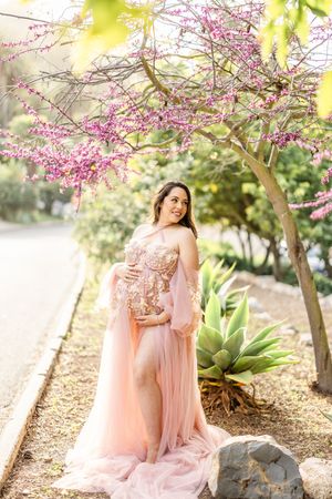 Maternity photos in a garden with blooming pink trees and succulents.