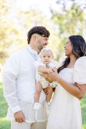 A family shares a joyful moment together outdoors wearing coordinated white outfits.