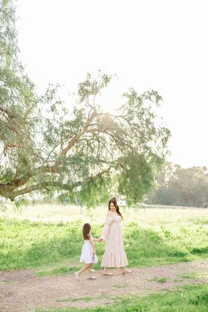 Gentle moment captured under weeping willow trees in a serene meadow setting.