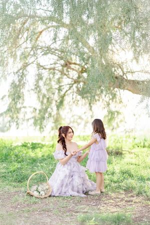 Dreamy spring scene under a willow tree with flowing dresses and flower basket.