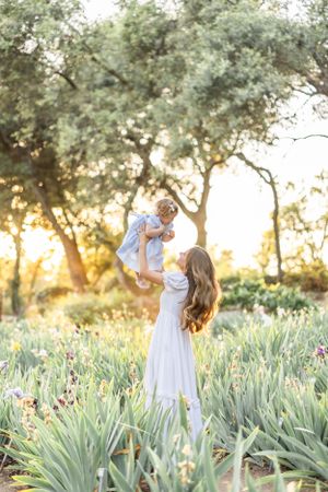 Family enjoys playful moment together in garden with iris flowers during golden hour.