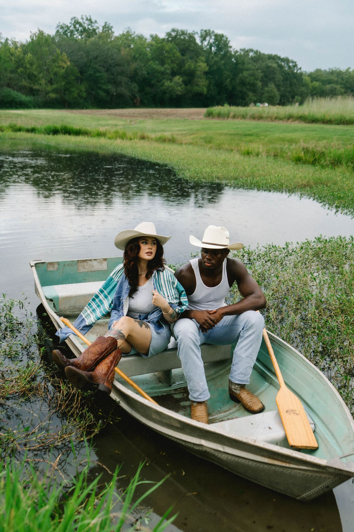 Couple relaxing in small boat on peaceful lake surrounded by natural vegetation.