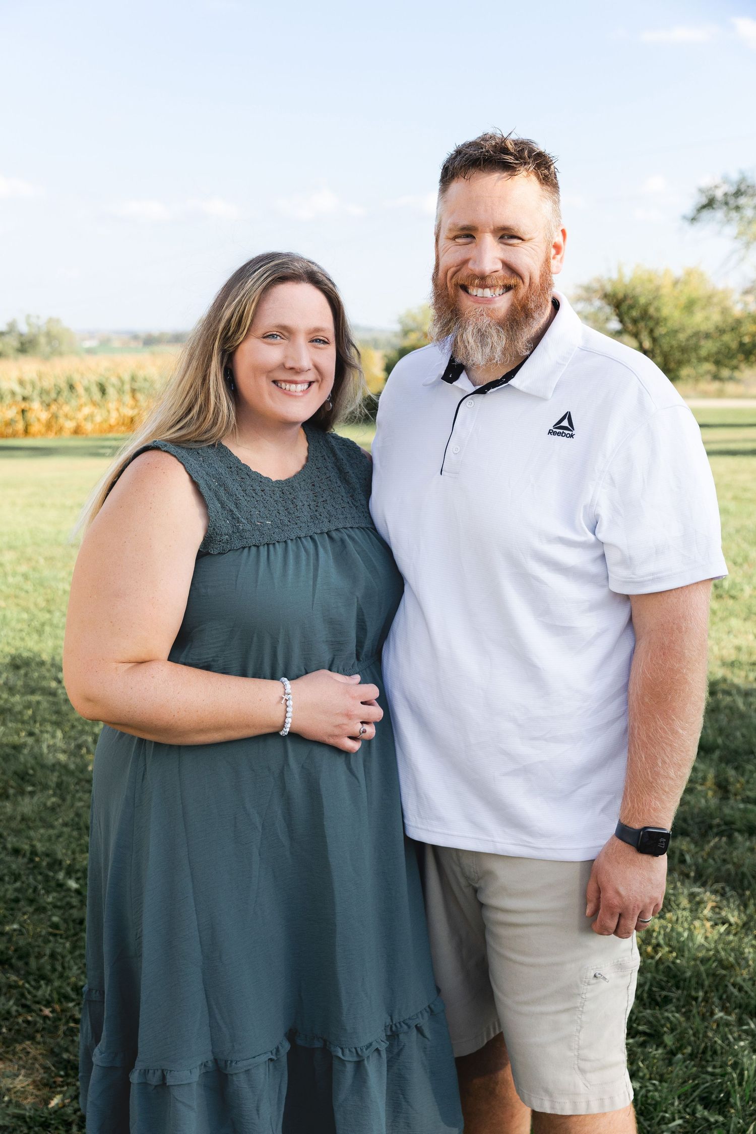 Couple posing together outdoors in casual attire against natural background.