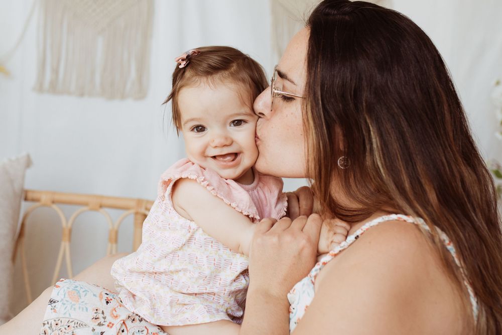 Joyful moment between parent and smiling baby in pink dress.