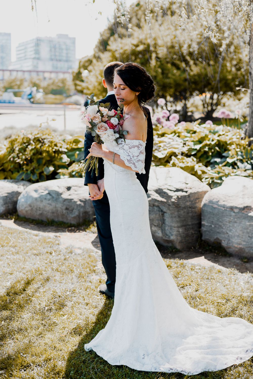 beautiful shot of bride holding a bouquet of flowers with the groom in the background in music garden at golden hour