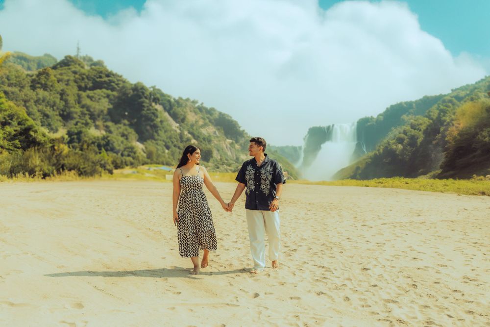 beutfull couple photo walking infront of  waterfall on a beach