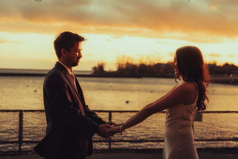 golden hour photo of a couple holding each others hands infront of the toronto lake