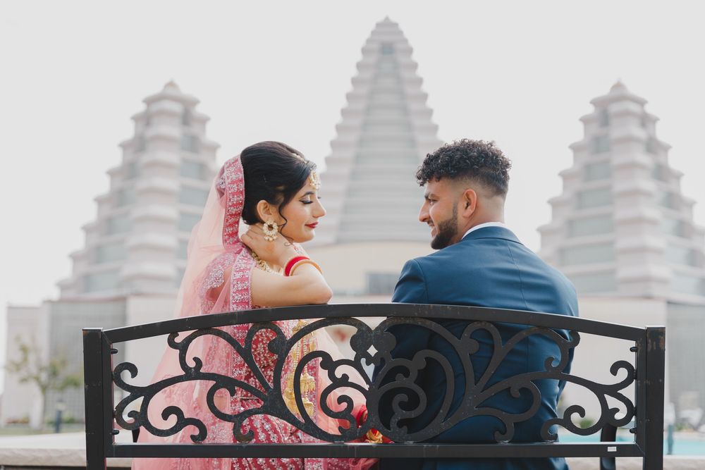 bride and groom in front of an indian hindu temple looking at each other with love
