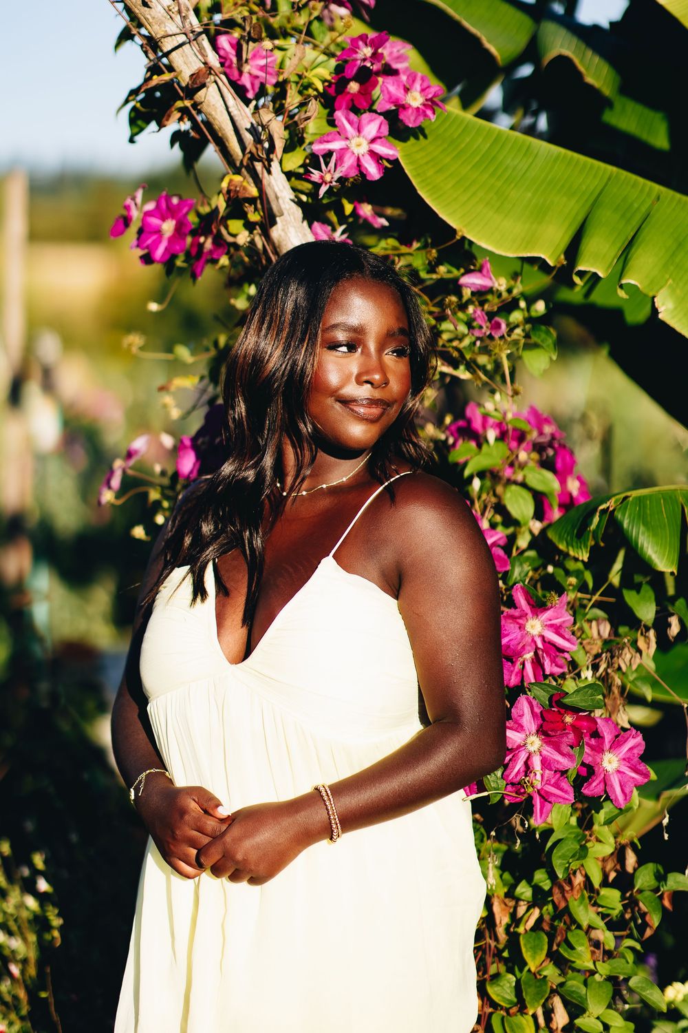 A portrait photoshoot in a garden setting with pink flowers and lush greenery creating a vibrant natural backdrop.