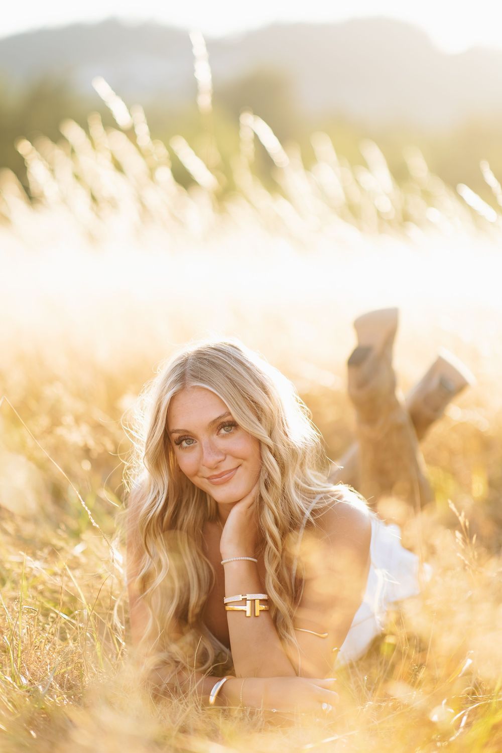 A dreamy outdoor portrait photoshoot in a golden wheat field during sunset with soft natural lighting.