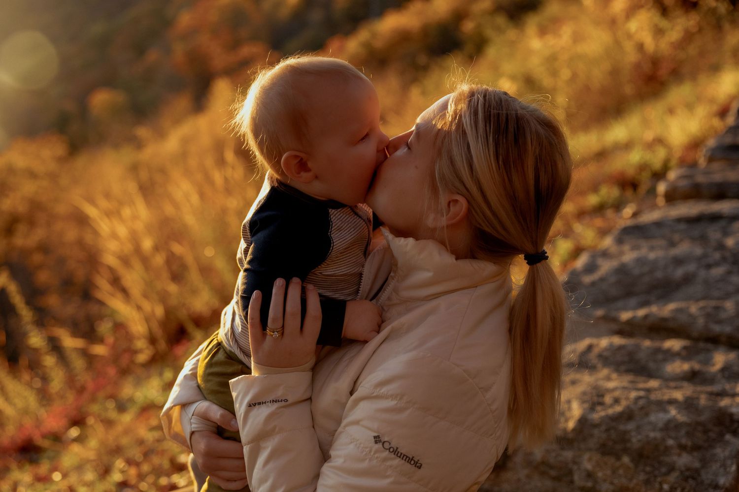 A tender moment shared between parent and child set against warm autumn foliage at golden hour.