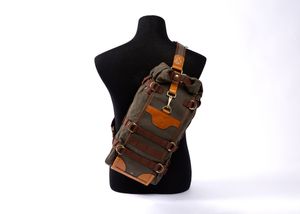 Brown leather steampunk crossbody bag with brass hardware displayed on black mannequin torso against white background.