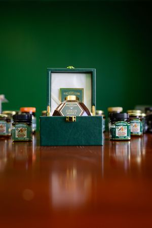 Small glass jars displayed in a row on a wooden surface with a green wall background and a framed picture.