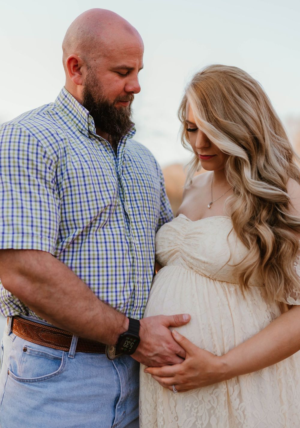 Expecting couple sharing tender moment in outdoor setting.