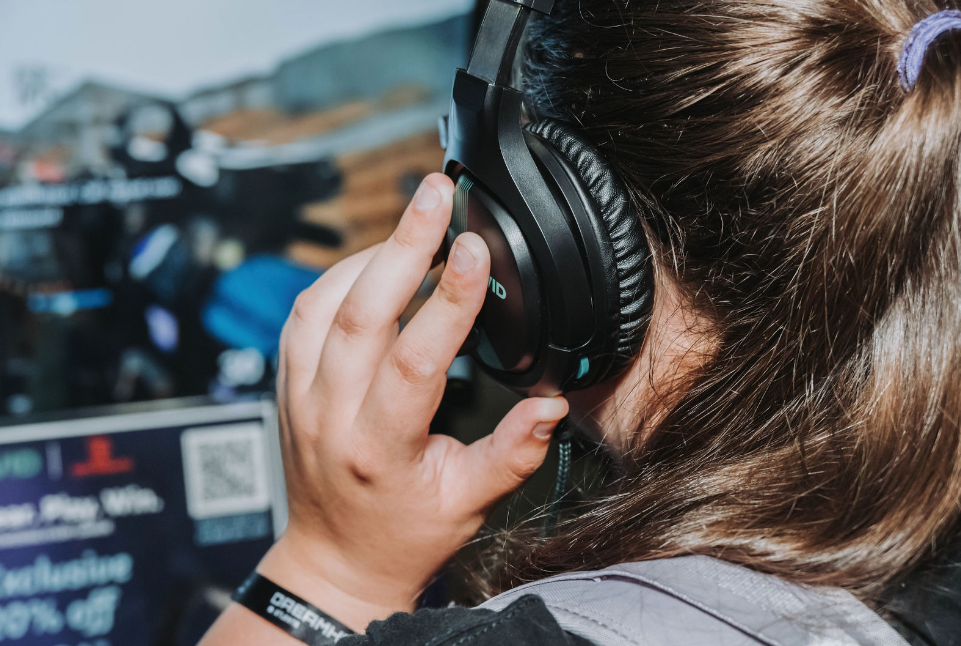Close-up of someone wearing large black headphones while sitting at a computer desk.
