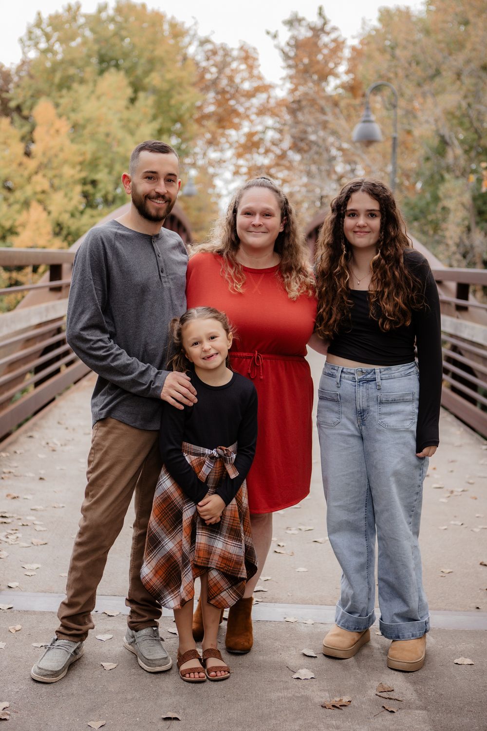Casual family portrait session on wooden bridge during autumn season.