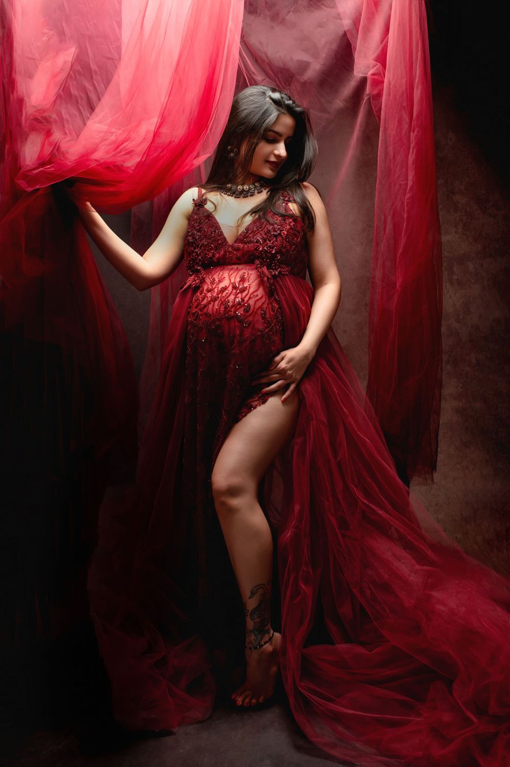 Artistic fashion photography featuring flowing red fabric and dramatic lighting in a dark studio setting.