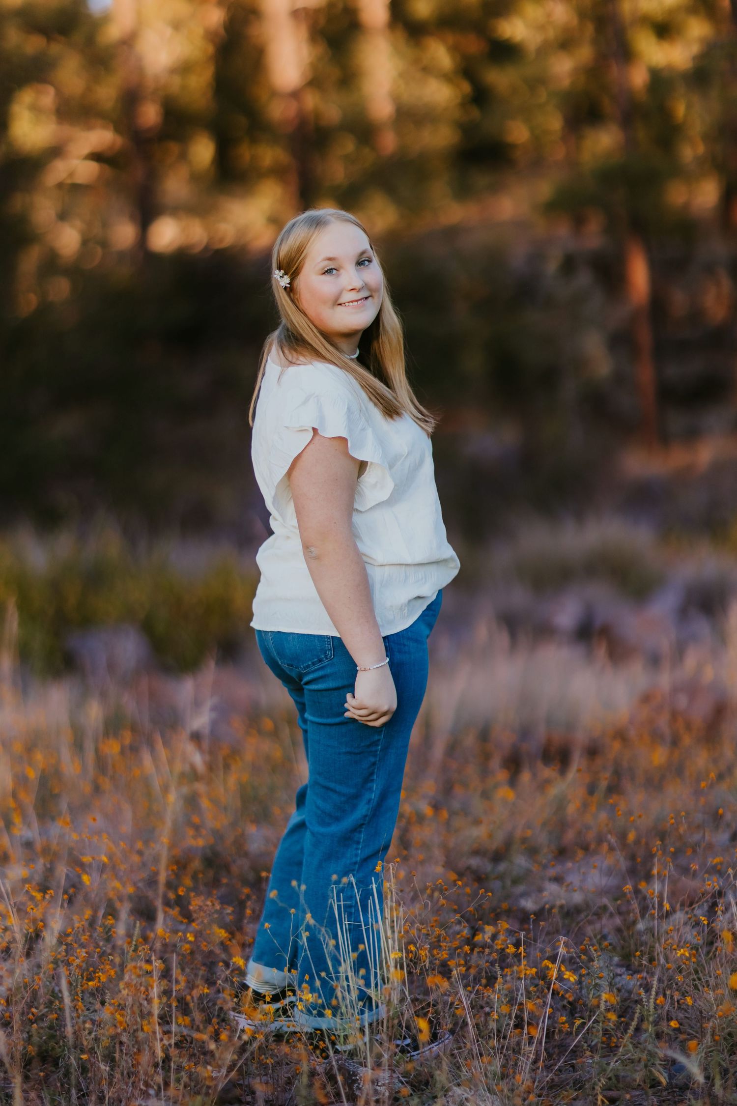 White top and denim outfit captured in field of purple wildflowers at sunset.