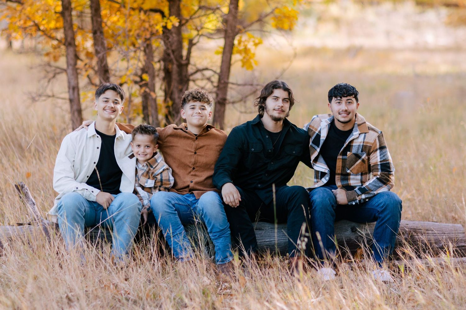 A group sitting together outdoors with fall foliage and golden sunlight in the background.