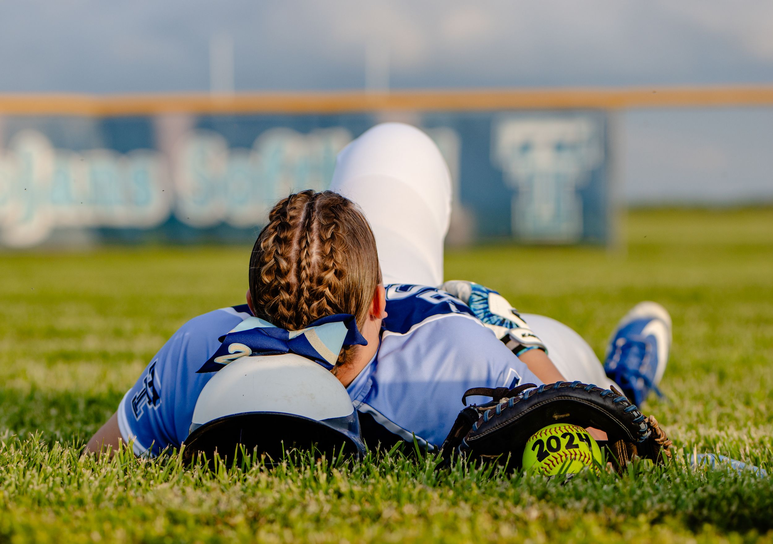 A player in blue uniform rests on grass field during sports practice.