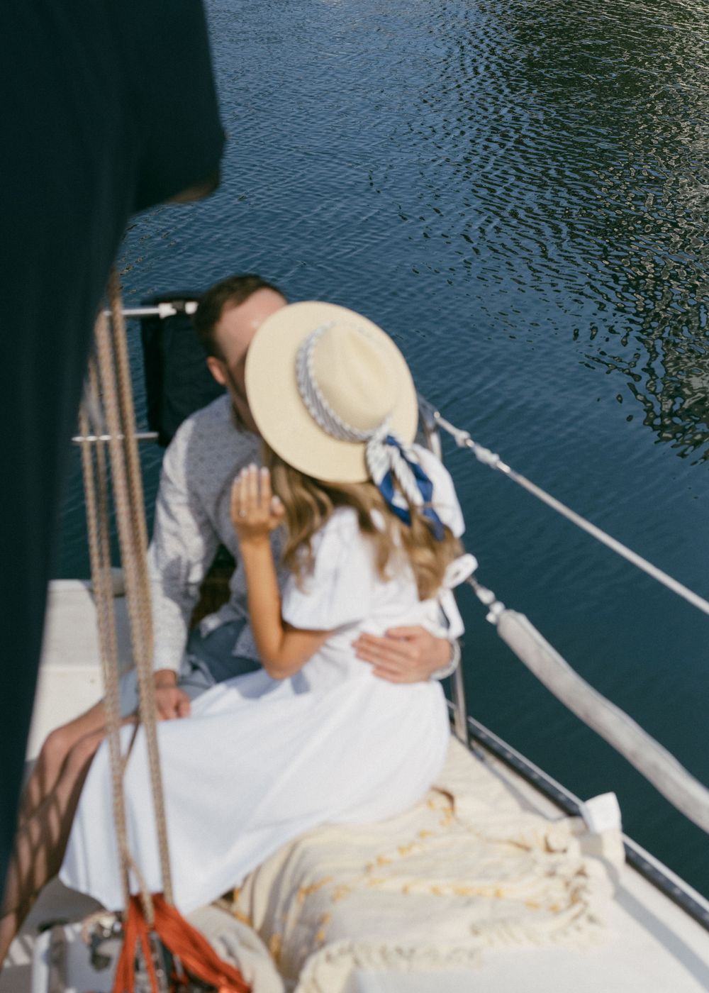 Sequence of intimate moments between a couple on a sailboat wearing summer attire.