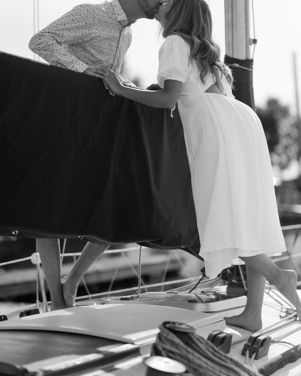 Black and white photos of a couple sharing tender moments on a boat deck.
