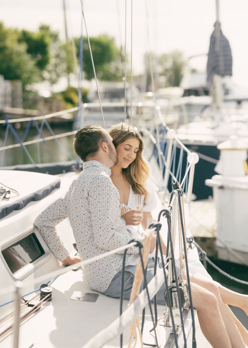 A romantic moment shared between two people on a sailboat during a sunny afternoon.