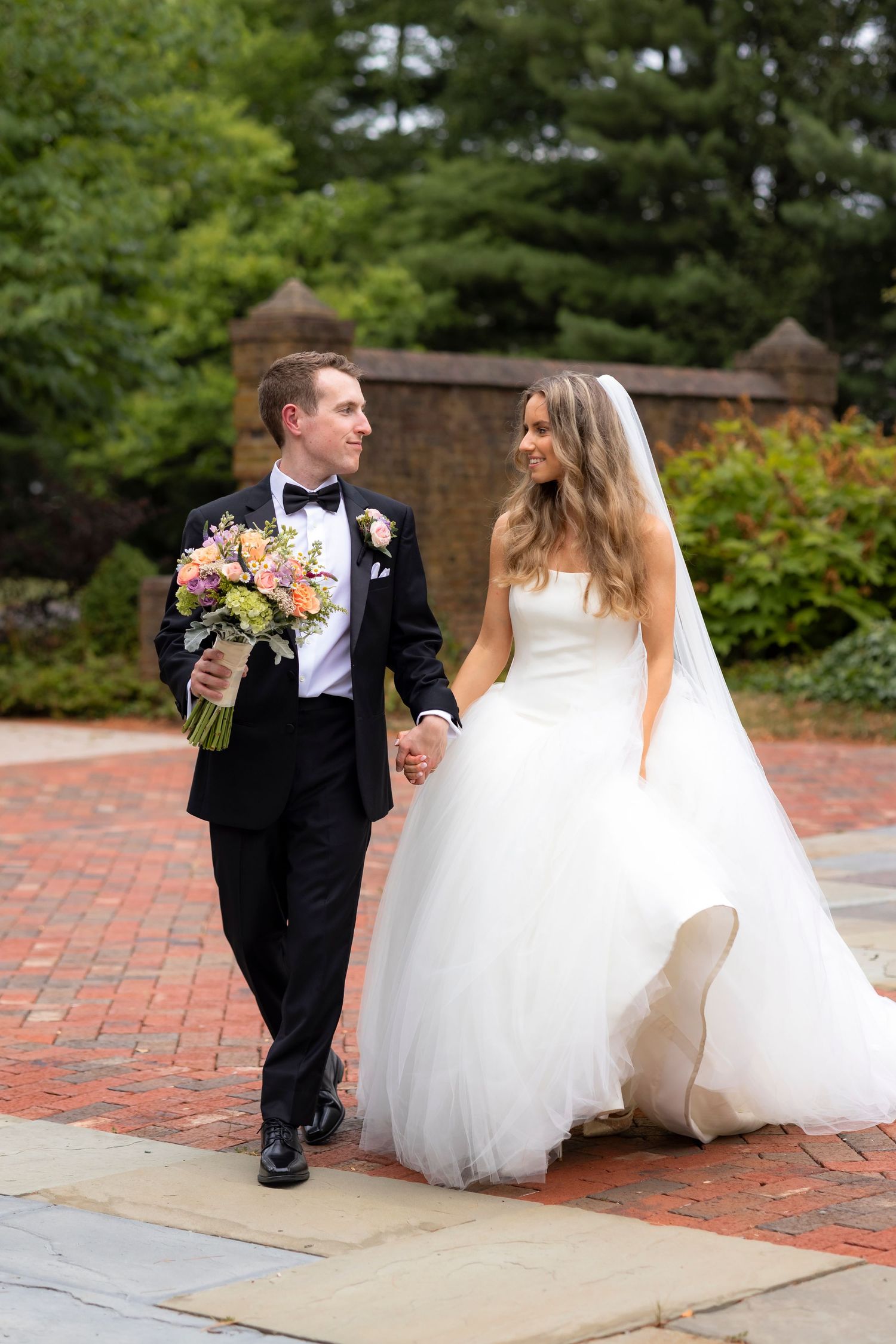 A bride in a white dress and groom in a light gray suit share a romantic kiss during their wedding ceremony.