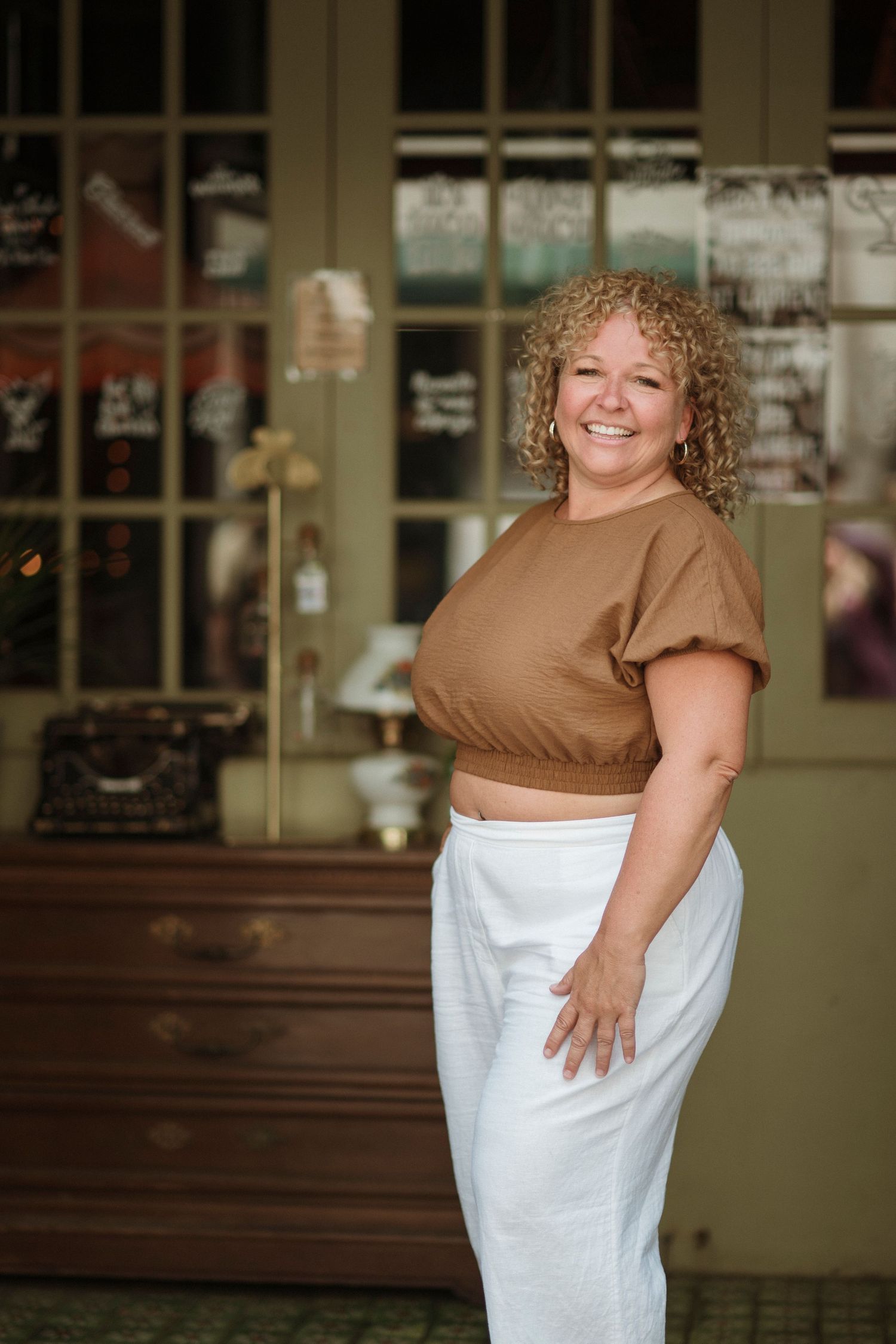 A series of four candid photos showing someone wrapped in a white towel and brown top posing playfully against a storefront.