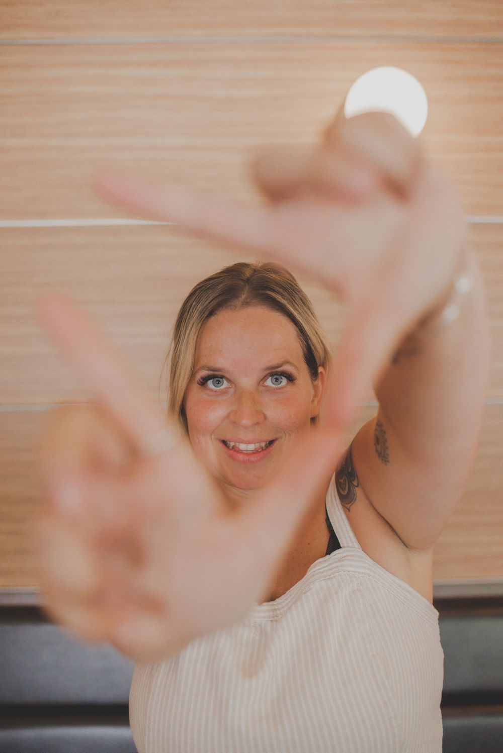 Playful portrait with peace signs and natural lighting against wooden background.