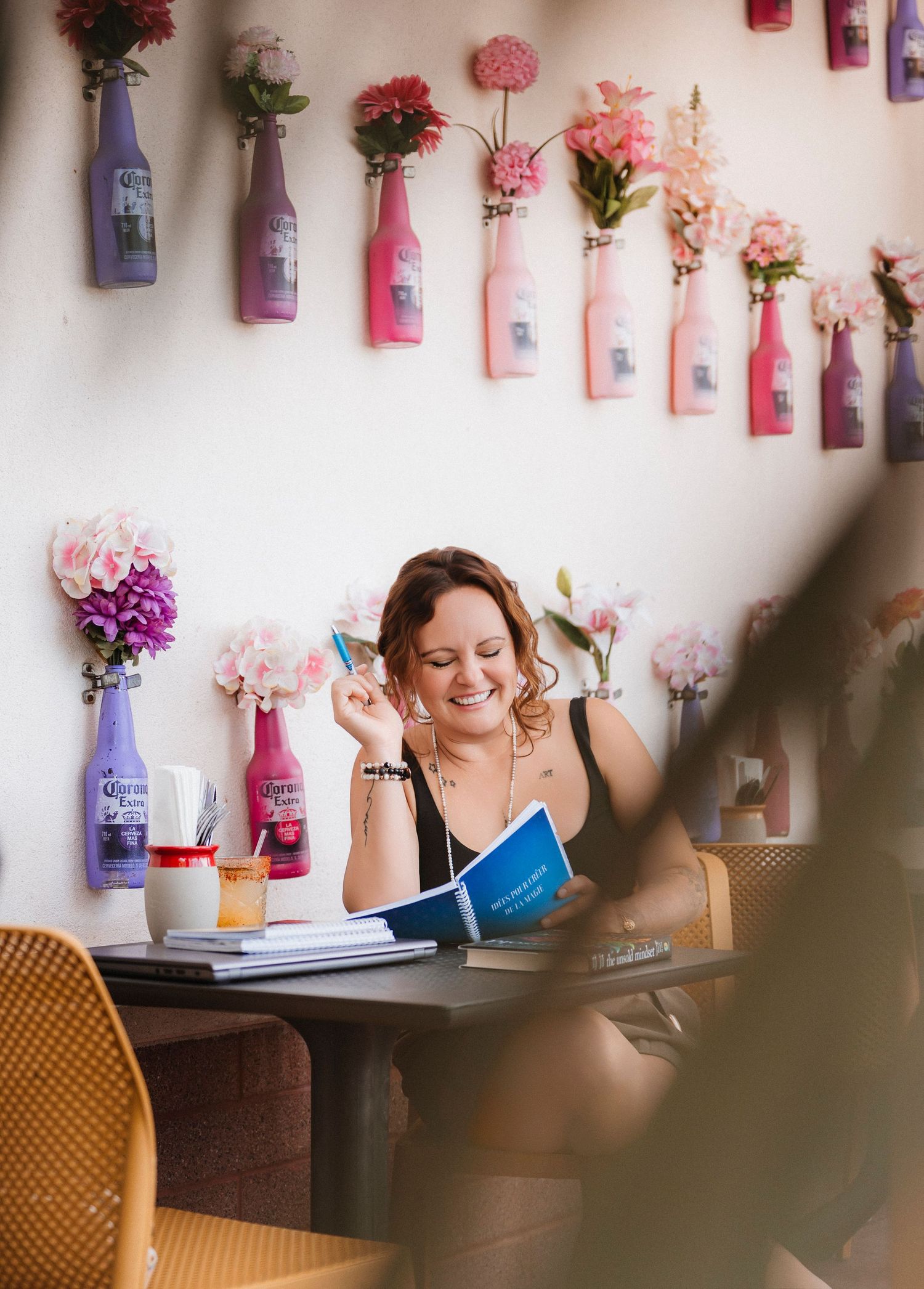 Decorative pink and purple flowers hang from the wall above a cozy reading nook with a wooden table.