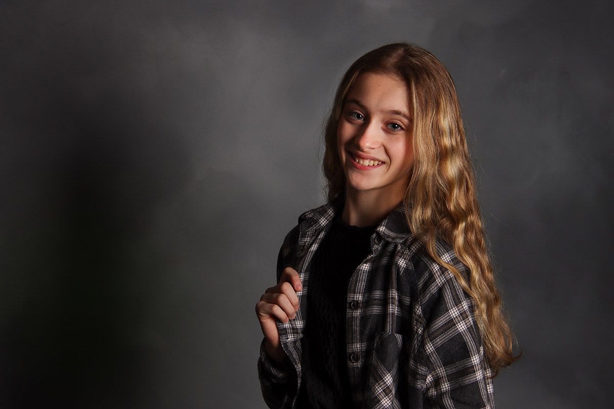 portrait of a tween girl in a flannel on a gray backdrop with dramatic lighting. Salem and Gloucester County tween Photographer