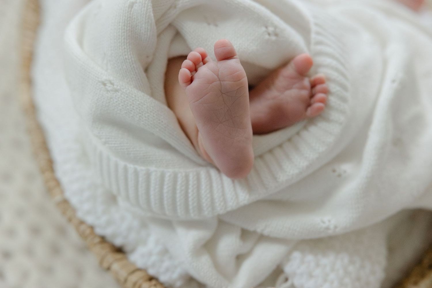Tiny newborn baby feet wrapped in soft white knitted blanket on textured background. Connecticut Newborn Photographer, Ashley Nielsen Studio
